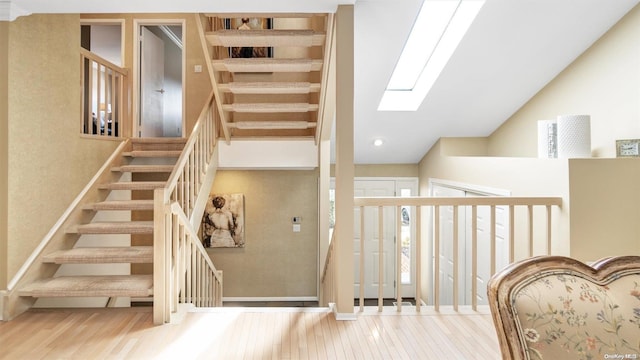 staircase with hardwood / wood-style flooring and a skylight