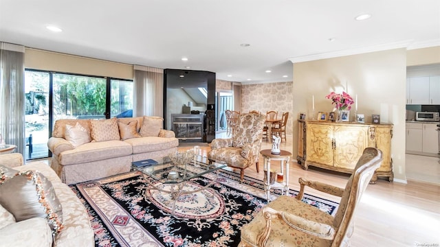 living room with crown molding, light wood-type flooring, and a fireplace