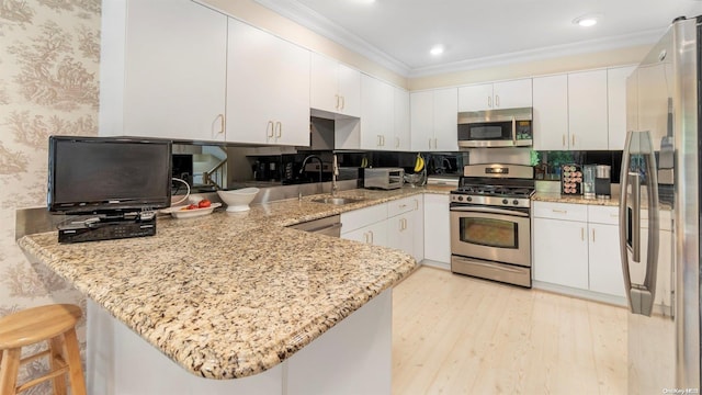 kitchen featuring kitchen peninsula, appliances with stainless steel finishes, light stone countertops, a kitchen breakfast bar, and white cabinets