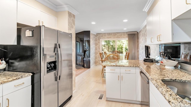 kitchen with light hardwood / wood-style floors, light stone counters, white cabinetry, and stainless steel appliances