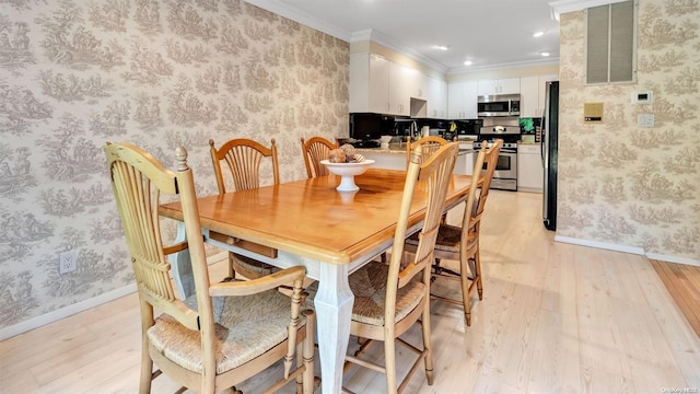 dining area with crown molding and light hardwood / wood-style floors