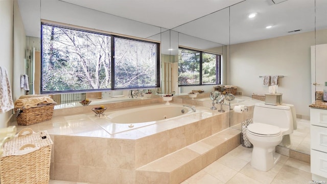 bathroom featuring tile patterned flooring, toilet, and tiled tub