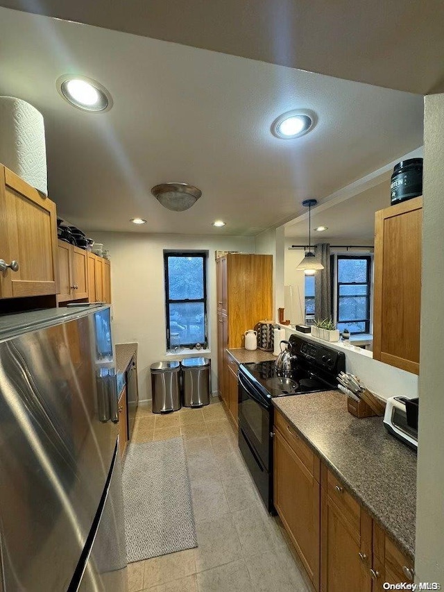 kitchen featuring decorative light fixtures, stainless steel fridge, and black / electric stove