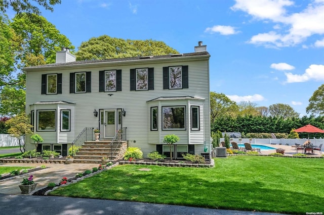 view of front of house with cooling unit, a fenced in pool, a patio, and a front yard