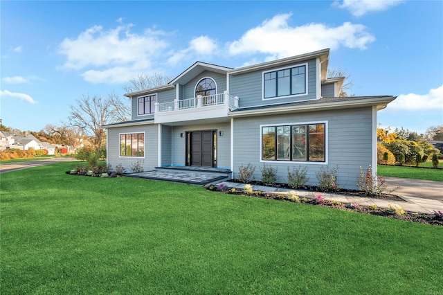 rear view of property with a balcony and a lawn