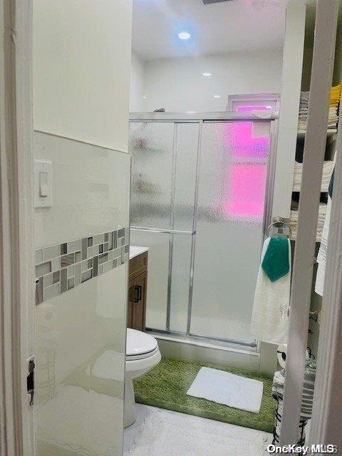 bathroom with vanity, an enclosed shower, and toilet