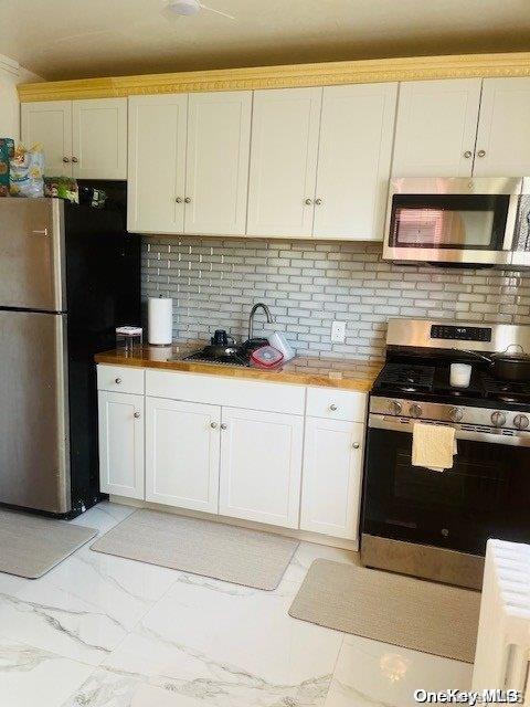 kitchen with decorative backsplash, sink, white cabinets, and appliances with stainless steel finishes