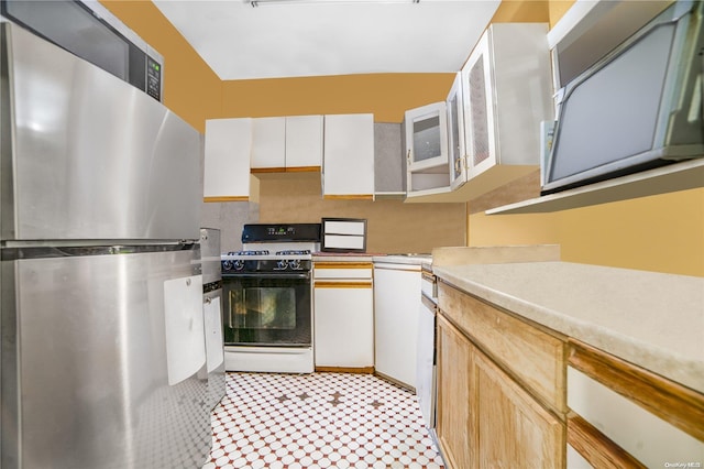 kitchen with stainless steel fridge, white range with gas stovetop, and white cabinetry