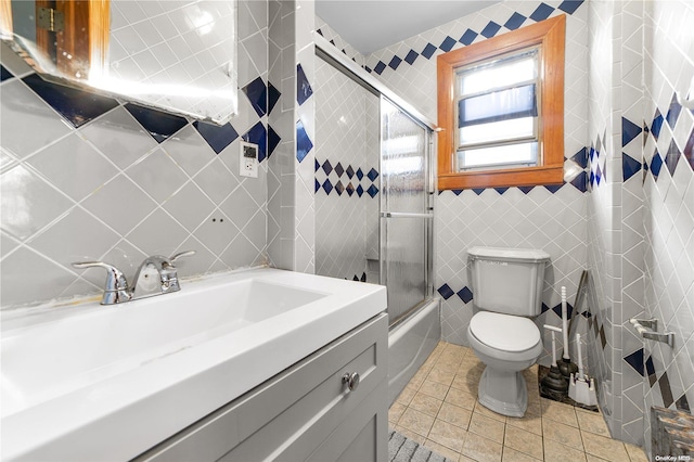 full bathroom featuring tile patterned flooring, bath / shower combo with glass door, and tile walls