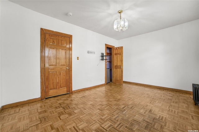 spare room featuring light parquet floors and an inviting chandelier