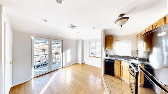 kitchen featuring tasteful backsplash, black appliances, sink, light hardwood / wood-style flooring, and light brown cabinets