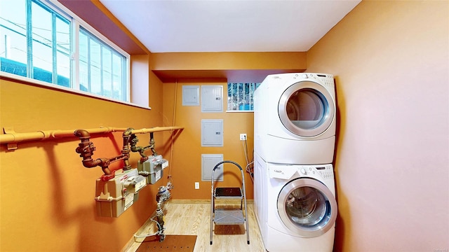 clothes washing area with stacked washer / dryer and light hardwood / wood-style flooring