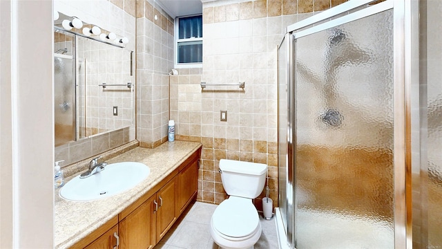 bathroom featuring tile patterned floors, a shower with door, vanity, tile walls, and toilet