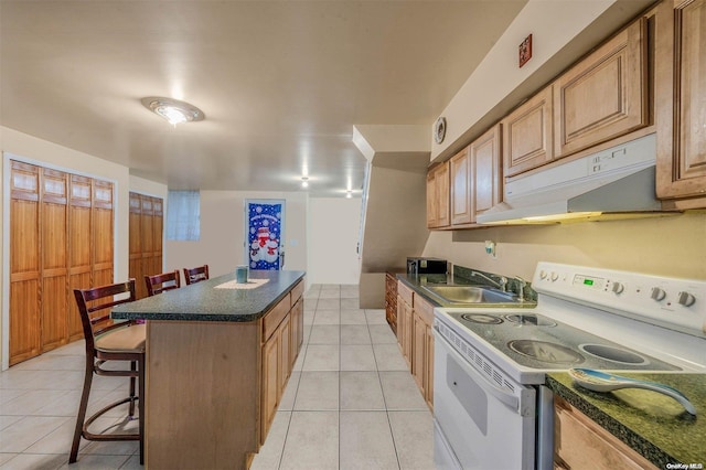 kitchen with a kitchen breakfast bar, white electric range oven, sink, light tile patterned floors, and a center island