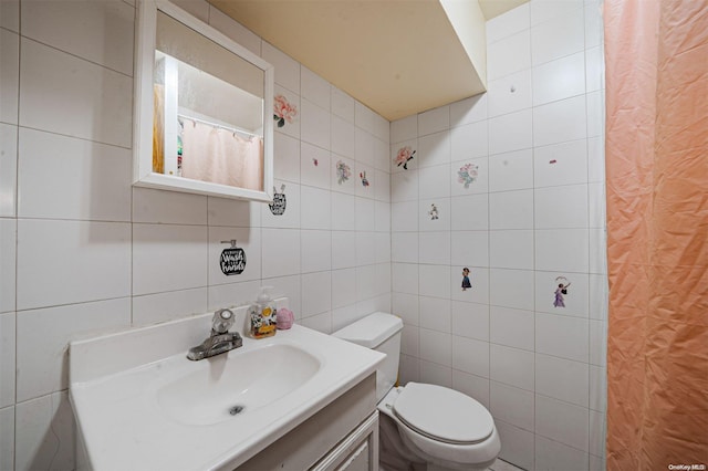 bathroom with vanity, toilet, and tile walls