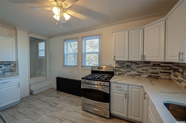 kitchen with crown molding, white cabinets, light stone counters, and stainless steel gas stove