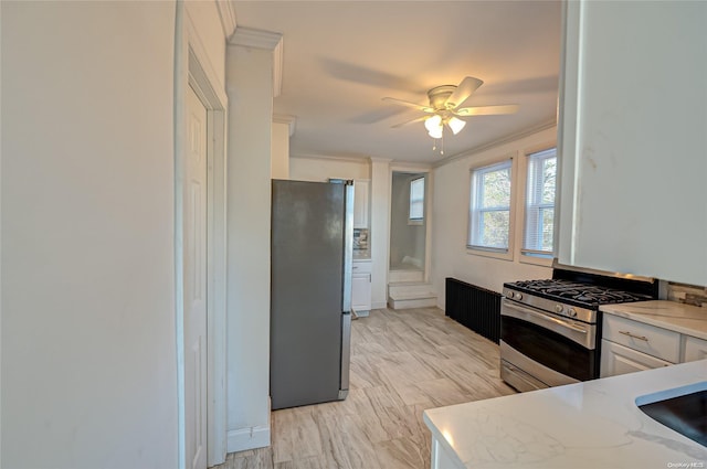 kitchen featuring white cabinetry, ornamental molding, ceiling fan, light stone counters, and stainless steel appliances