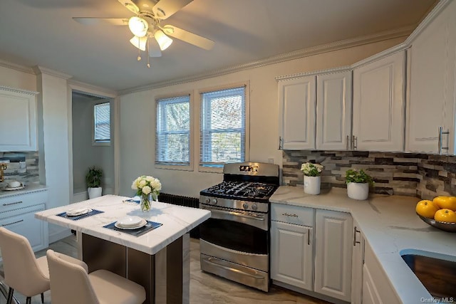 kitchen with stainless steel gas stove, white cabinetry, a kitchen breakfast bar, and crown molding