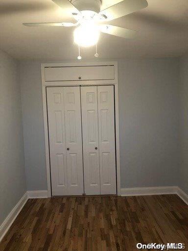 unfurnished bedroom featuring ceiling fan, dark hardwood / wood-style floors, and a closet