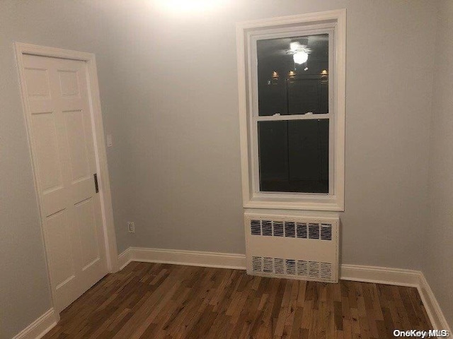 unfurnished room featuring dark hardwood / wood-style flooring and radiator