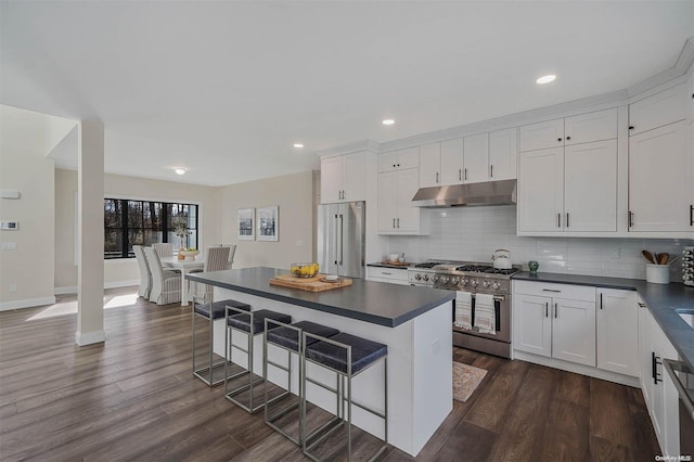 kitchen featuring white cabinets, dark hardwood / wood-style floors, high end appliances, and a breakfast bar area