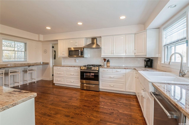 kitchen with white cabinetry, wall chimney range hood, dark wood-type flooring, and appliances with stainless steel finishes