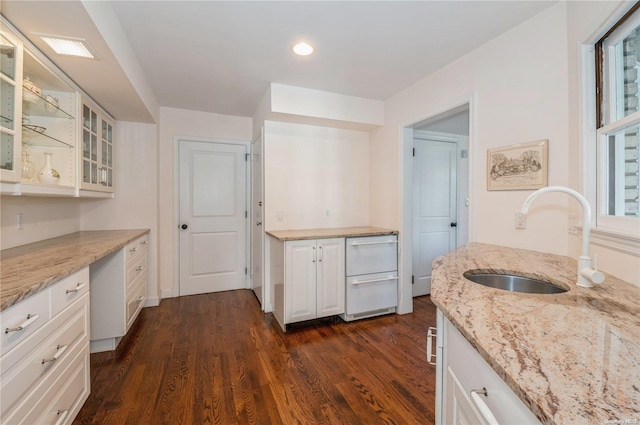 kitchen featuring white cabinets, light stone counters, dark wood-type flooring, and sink