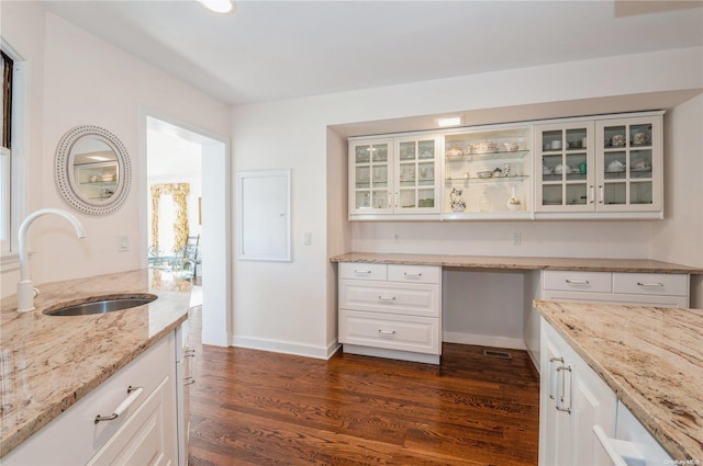 kitchen featuring white cabinets, light stone countertops, dark wood-type flooring, and sink