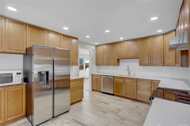 kitchen featuring sink, tasteful backsplash, light wood-type flooring, range hood, and appliances with stainless steel finishes