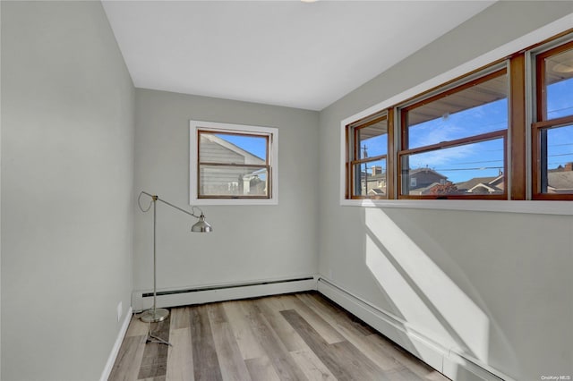 unfurnished room featuring light wood-type flooring and baseboard heating