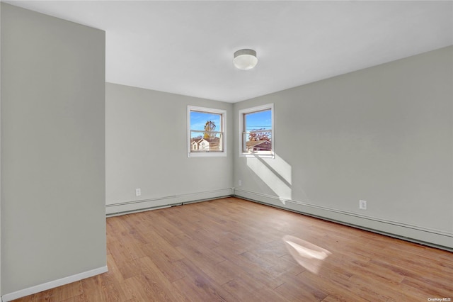 unfurnished room featuring baseboard heating and light hardwood / wood-style floors