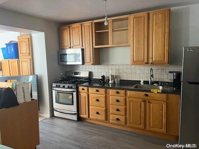 kitchen featuring backsplash, dark wood-type flooring, sink, and stainless steel appliances