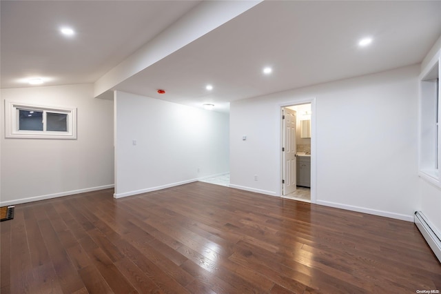 empty room with dark hardwood / wood-style floors, lofted ceiling, and a baseboard radiator