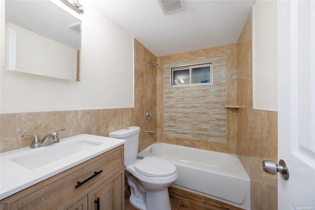 full bathroom with vanity, tiled shower / bath combo, tile walls, and toilet