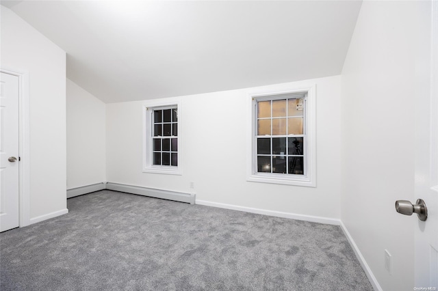 carpeted empty room with a baseboard radiator and vaulted ceiling