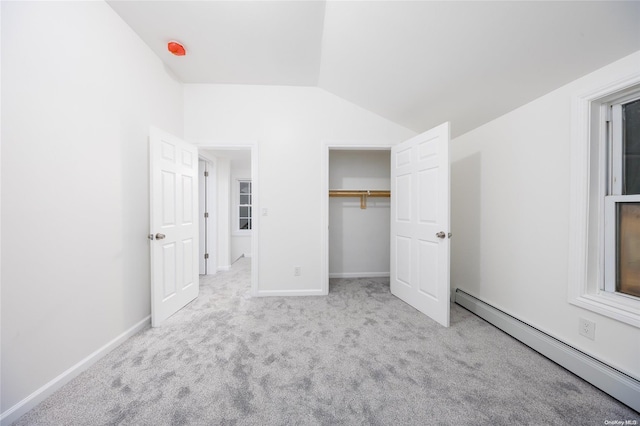 unfurnished bedroom featuring baseboard heating, light colored carpet, and vaulted ceiling