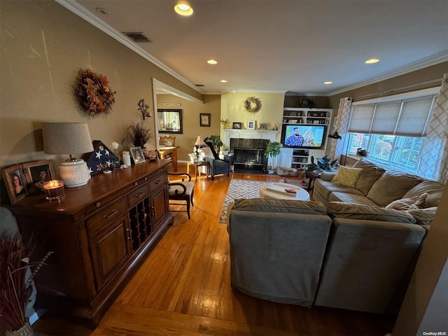 living room with a tile fireplace, light wood-type flooring, and ornamental molding