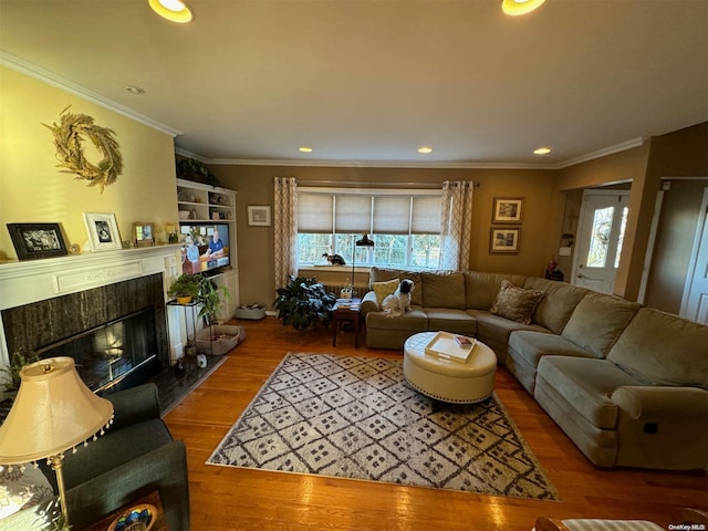 living room featuring a tile fireplace, crown molding, and hardwood / wood-style flooring