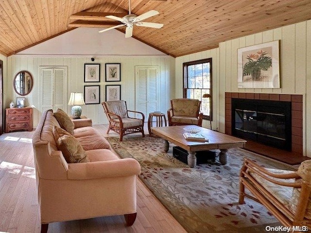 living room featuring lofted ceiling with beams, ceiling fan, light wood-type flooring, and wooden ceiling