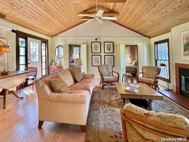 living room featuring lofted ceiling, wooden ceiling, wooden walls, light hardwood / wood-style flooring, and ceiling fan