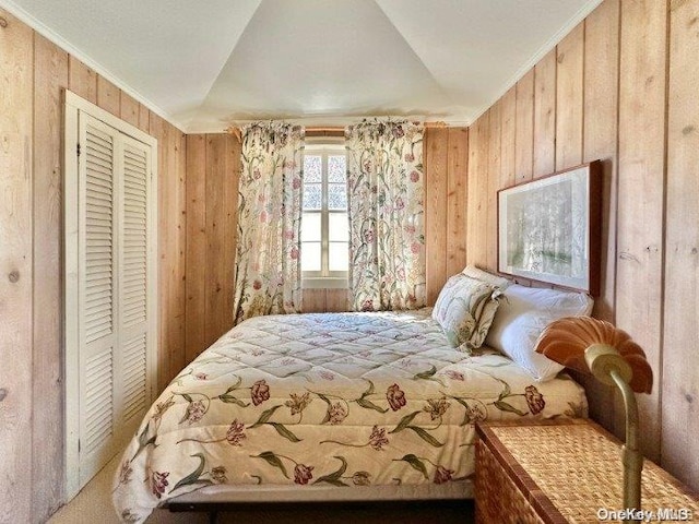 bedroom with wood walls, crown molding, and a closet