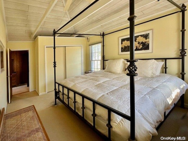 bedroom with carpet flooring, vaulted ceiling with beams, a closet, and wood ceiling