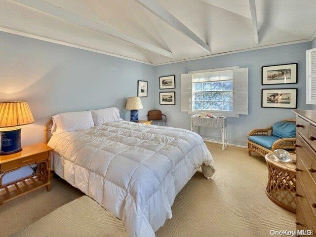 carpeted bedroom with vaulted ceiling with beams