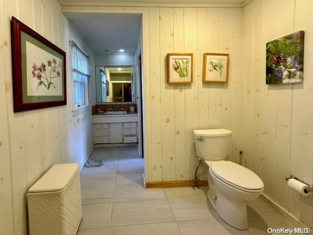 bathroom featuring tile patterned floors, toilet, and wooden walls