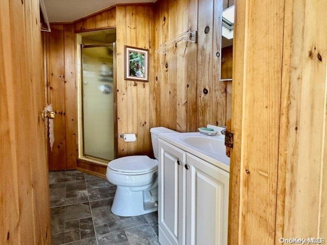 bathroom with vanity, wood walls, toilet, and walk in shower