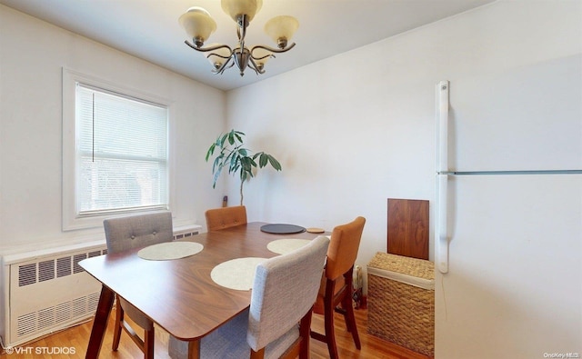 dining space featuring hardwood / wood-style floors, radiator, and a chandelier