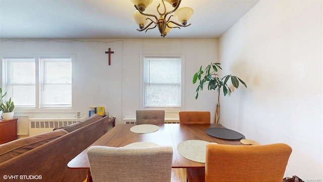 dining space with radiator heating unit, a chandelier, and hardwood / wood-style flooring