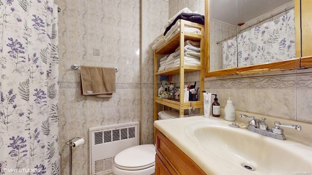 bathroom featuring curtained shower, radiator heating unit, toilet, vanity, and tile walls