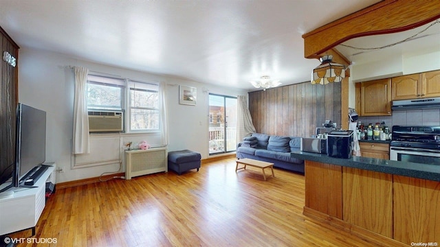 living room featuring radiator heating unit, an inviting chandelier, light hardwood / wood-style flooring, and cooling unit