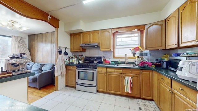 kitchen with stainless steel range, light wood-type flooring, backsplash, and sink